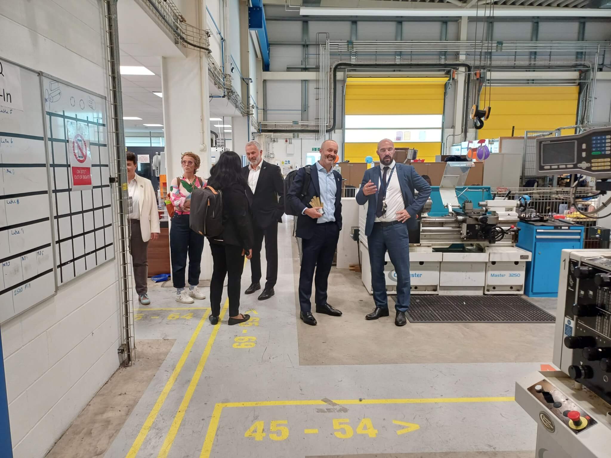 A group of people stood in a cavernous room full of engineering equipment.