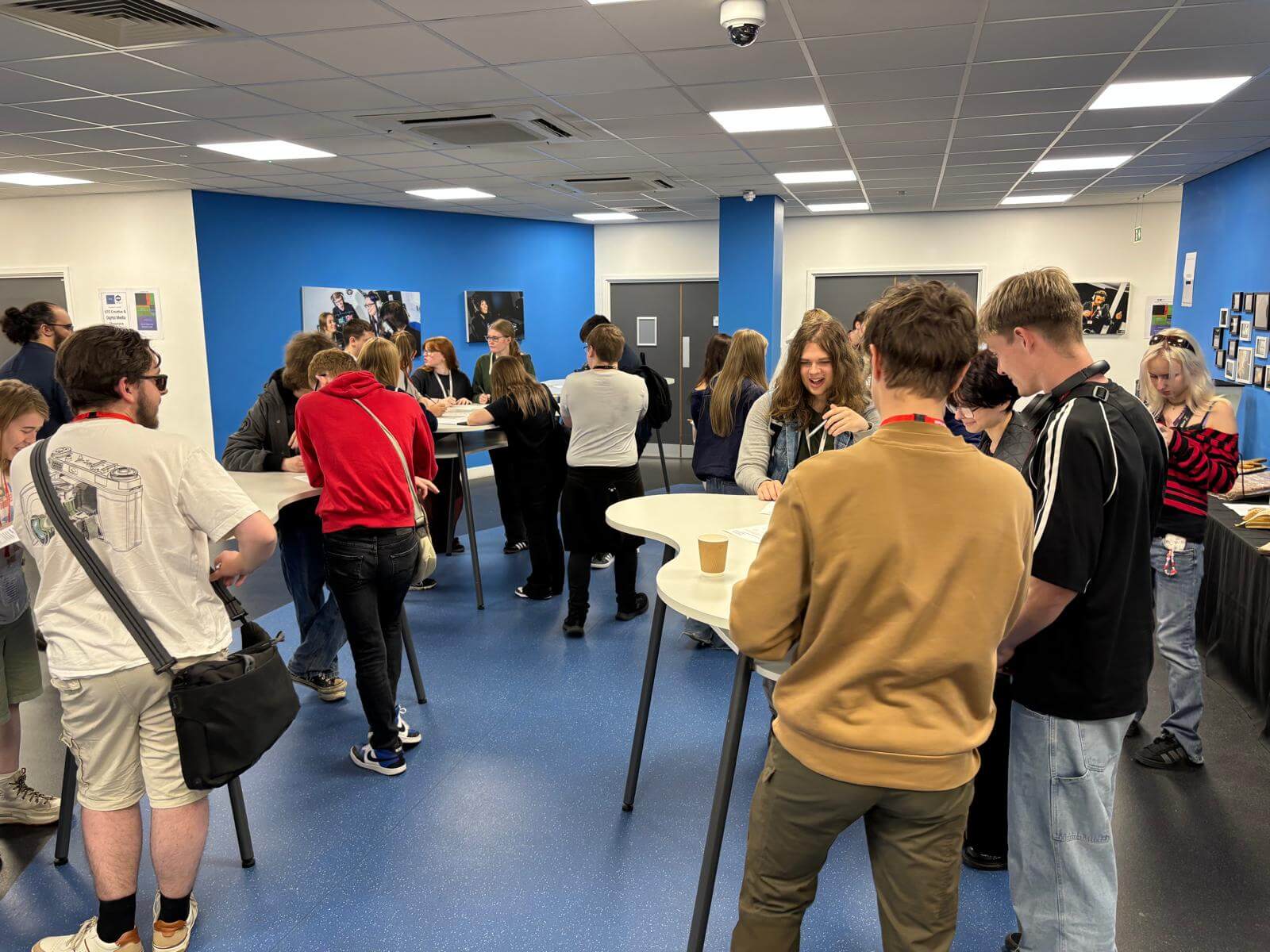 Students stood gathered around high tables, taking part in a collaborative activity.