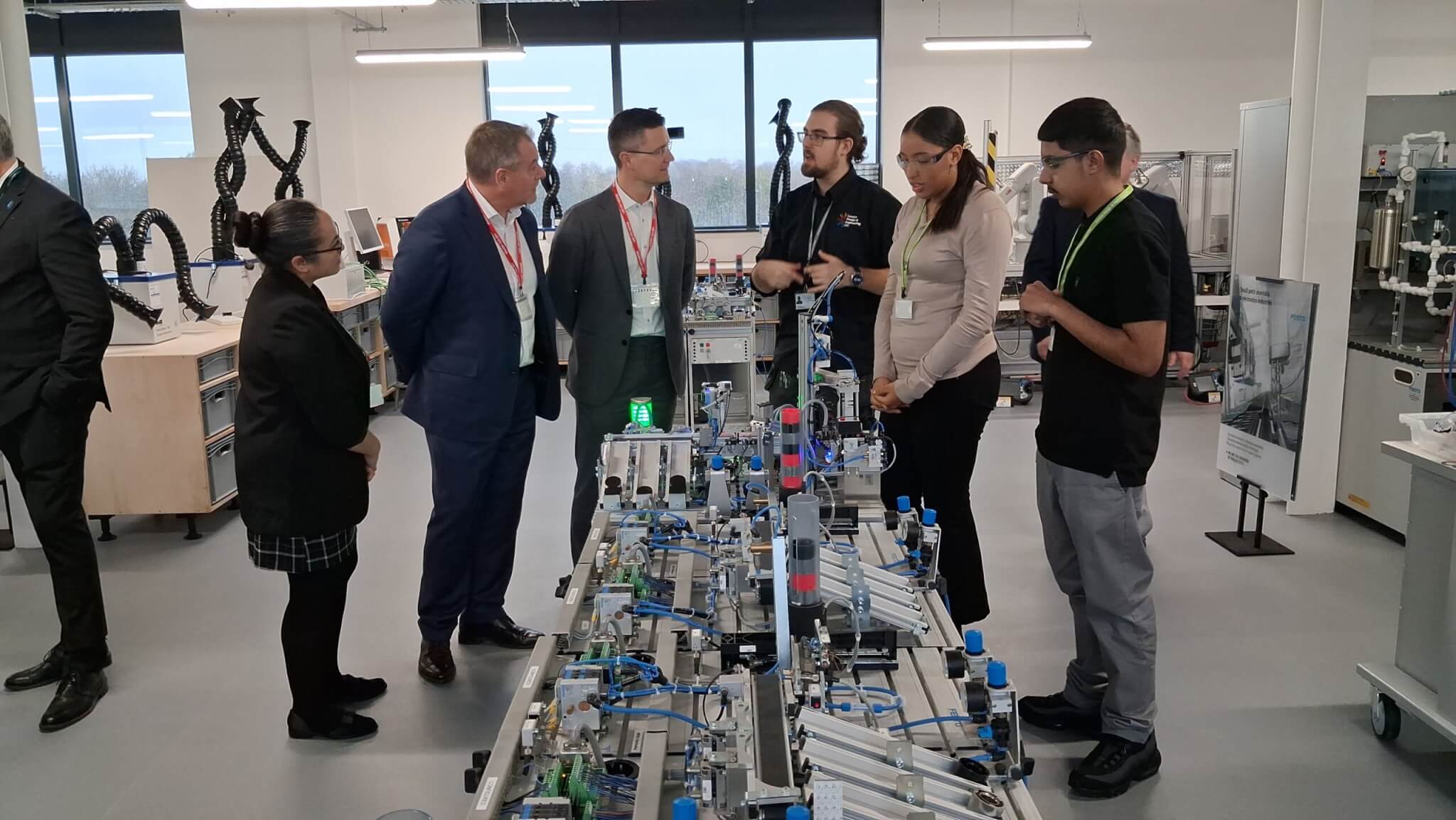 A group of people gathered around a model production line.