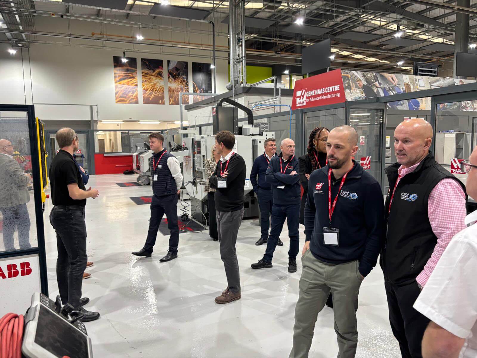 A group of diverse individuals gathered in a factory, discussing operations and inspecting machinery.